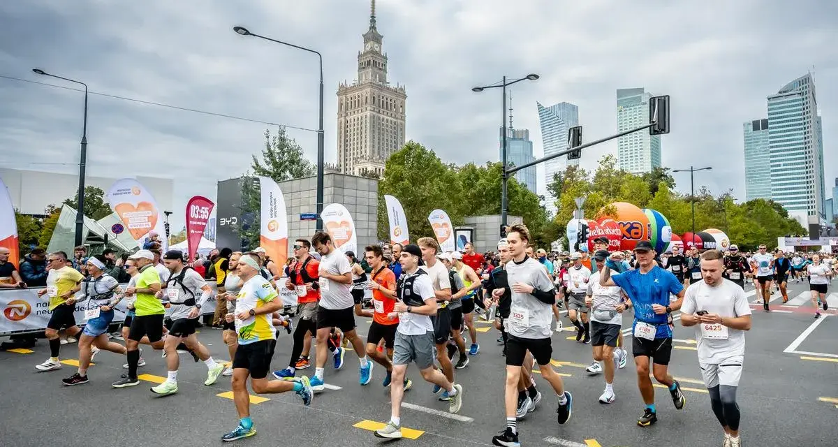 Uczestnicy biegną w maratonie, pokonując dystans 42,195 kilometrów. W tle Pałac Kultury i Nauki.