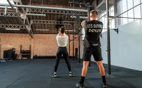 Para ćwiczy z kettlebell w siłowni CrossFit.