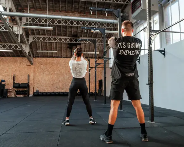 Para ćwiczy z kettlebell w siłowni CrossFit.