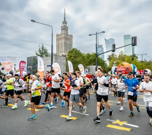 Uczestnicy biegną w maratonie, pokonując dystans 42,195 kilometrów. W tle Pałac Kultury i Nauki.