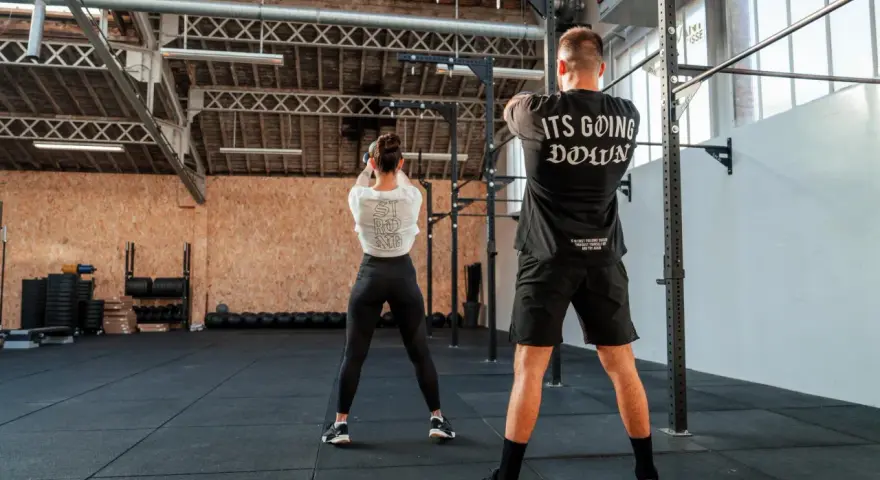 Para ćwiczy z kettlebell w siłowni CrossFit.