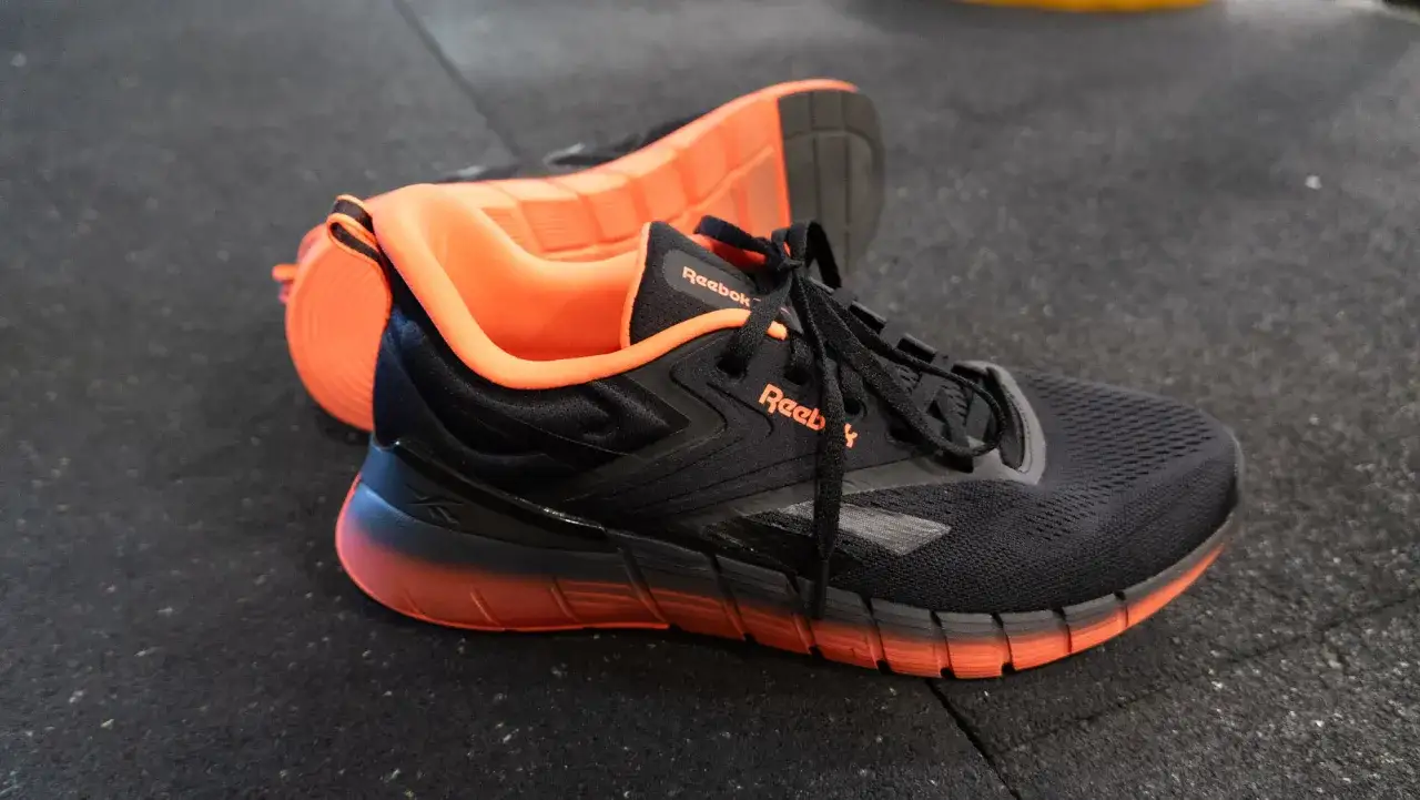 Czarne buty Reebok z pomarańczowymi akcentami, idealne jako buty do crossfitu.