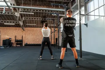 Para ćwiczy z kettlebell w siłowni CrossFit.
