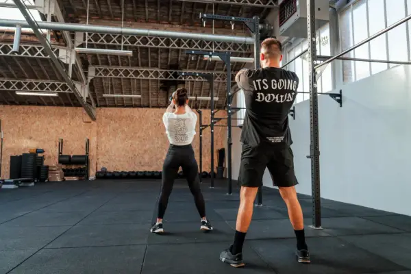 Para ćwiczy z kettlebell w siłowni CrossFit.